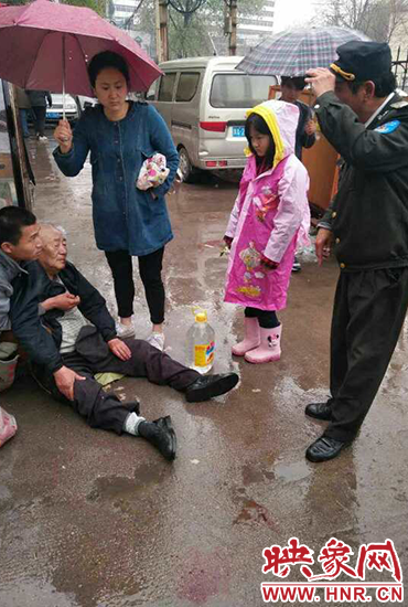 女孩為倒地老人撐傘。