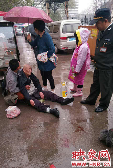 女孩為倒地老人撐傘。