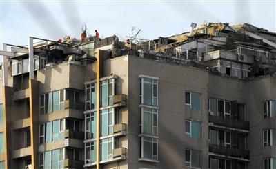 　　昨日，身穿橘黃色馬甲的工作人員在人濟(jì)山莊樓頂拆除違章建筑。新京報(bào)記者 吳江 攝