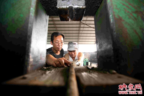 劉金玉正與工友一起用自己發(fā)明的綜合液壓機(jī)對(duì)廢舊錨桿進(jìn)行軋直處理