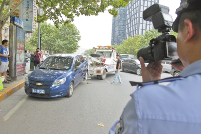 在金水路，交警對(duì)在機(jī)動(dòng)車道違法停放的車輛施行拖離