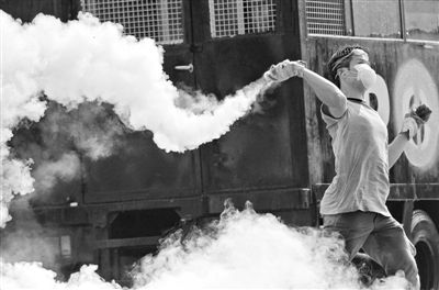 12月2日，泰國(guó)曼谷，一名反政府示威者在總理府附近向負(fù)責(zé)執(zhí)勤的警察投擲催淚彈。英拉請(qǐng)求示威者不要再試圖占領(lǐng)政府工作部門，不要逼迫政府工作人員選邊站。