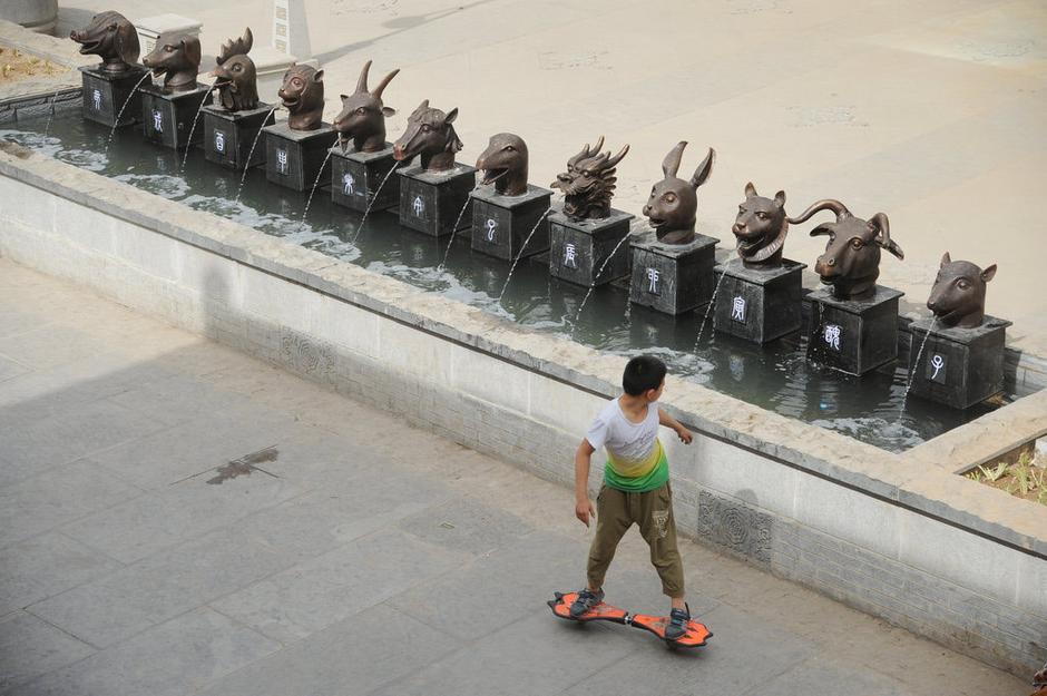 圖為一名市民從獸首旁經(jīng)過(guò)。