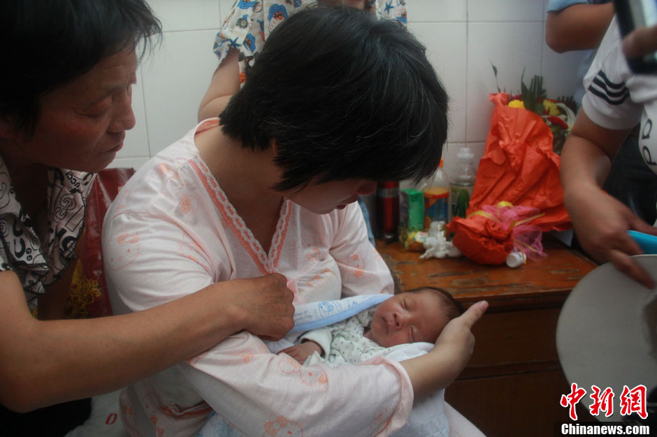 圖為久別重逢，獲救嬰兒母親悉心撫摸愛子。張一辰 攝