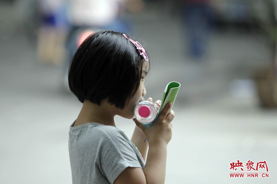 6月7日，鄭州回中考點(diǎn)，一名孩子拿著一瓶礦泉水，等待哥哥走出考場(chǎng)