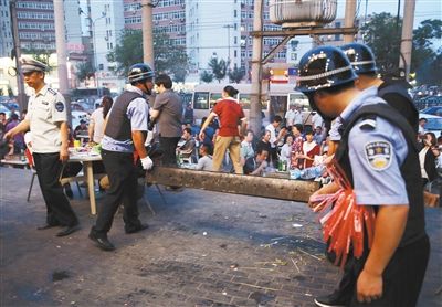 6月13日晚8點(diǎn)，朝陽(yáng)路和青年路交叉口西側(cè)，一次聯(lián)合執(zhí)法行動(dòng)中，輔警與協(xié)管抬走商戶(hù)的燒烤用具。新京報(bào)記者 尹亞飛 攝