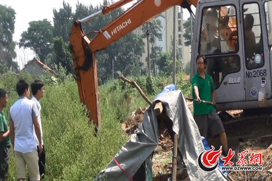 陳寶成手持自制刀斧守在挖掘機旁阻止便衣民警靠前。駕駛室內，張朋珂正向受害人郭曉剛身上澆汽油。（視頻截圖）