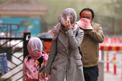 昨日下午，朝陽區(qū)豆各莊，行人將紗巾裹在頭上防沙塵。