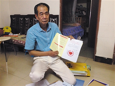 翻出一家網(wǎng)站贈(zèng)予的“中國(guó)好人”證書(shū)，區(qū)少坤單膝跪在地上，“你看，我是中國(guó)好人啊。” 范春旭 攝