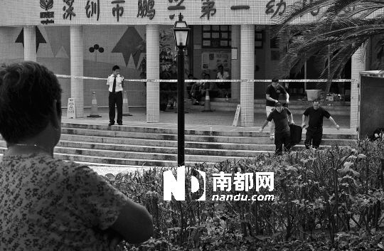 →7月19日，鵬興花園第一幼兒園門前，民警在現(xiàn)場進(jìn)行完勘查取證后，園長和保安的尸體被運走。南都記者 徐文閣 攝