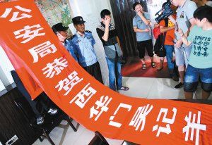 面對(duì)警方收繳的條幅，老板楊某也不好意思地用手遮擋臉