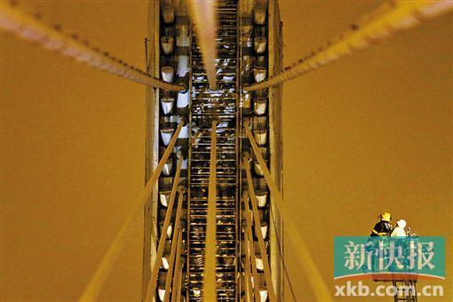 截至今日零時，男子仍未有下橋舉動。圖為公安和消防人員乘消防云梯在高空上和男子交談。