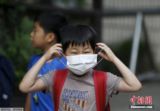 圖為當(dāng)?shù)貢r間2015年6月8日，韓國未停課的學(xué)校，學(xué)生課前戴口罩測體溫。