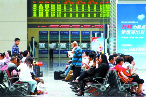 候車大廳溫度很高，一名乘客一手扇風、一手擦汗