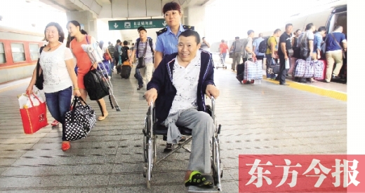 李剛手術后歸來，在車站工作人員幫助下走出鄭州火車站站臺  東方今報首席記者 張曉冬 攝