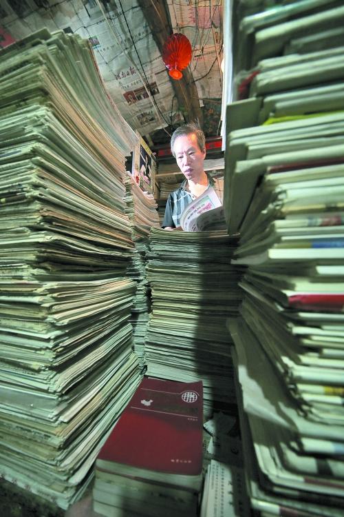 王曉民坐在寫字桌前，被報(bào)紙淹沒。
