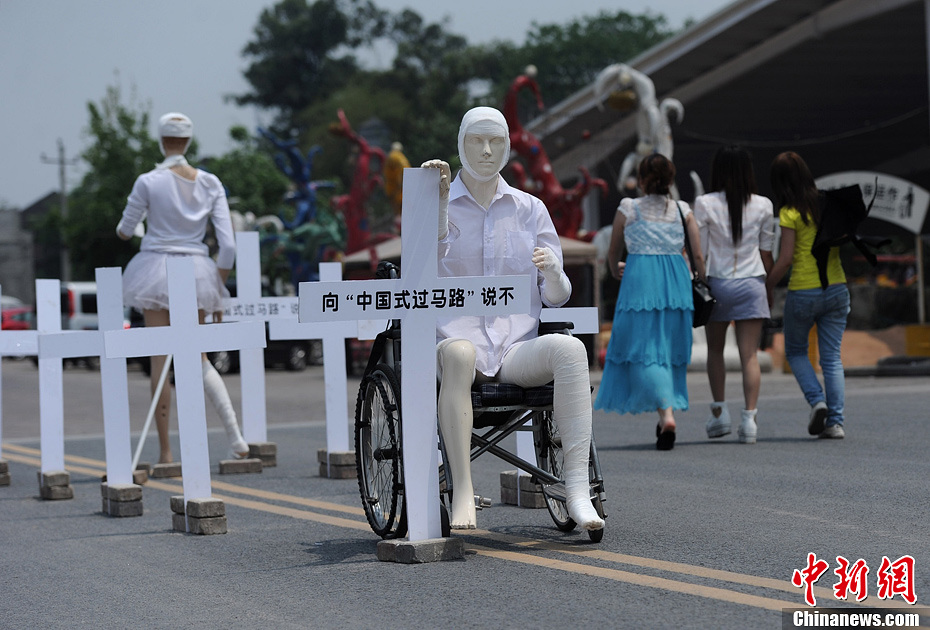 4月16日，重慶市洋人街上擺放著兩個(gè)受了傷的塑料人像“模特”，旁邊十字架上寫(xiě)著向“中國(guó)式過(guò)馬路”說(shuō)不