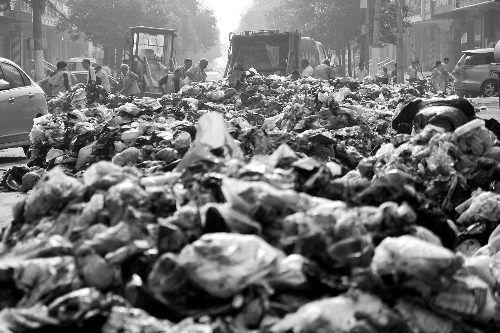 垃圾堆滿整個(gè)路口，環(huán)衛(wèi)工人們正在清理