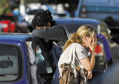 27日，遇難者親友在火災(zāi)現(xiàn)場(chǎng)旁哭泣。