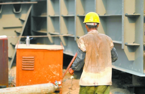 工地上，一建筑工人的衣服被汗水浸透。