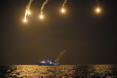 22日，搜救人員在照明彈的光亮下連夜搜救。