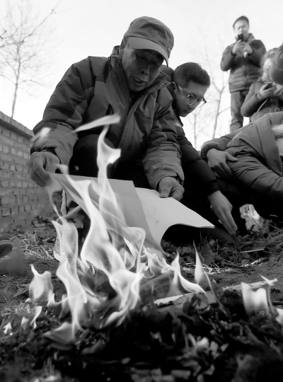 李三仁在兒子墳前焚燒再審無罪判決文書的復(fù)印件。新華社發(fā)