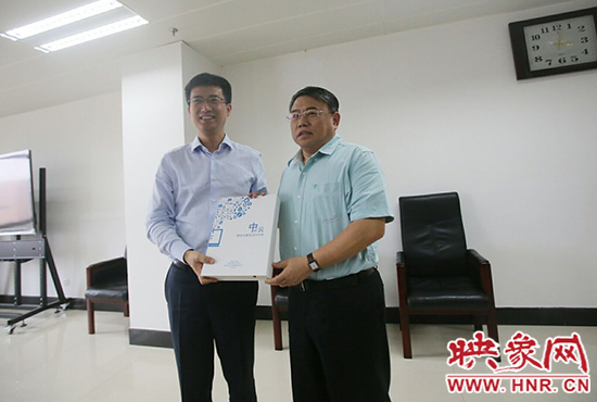 阿里云計算總裁胡曉明向河南省新聞出版廣電局局長朱夏炎遞交《中原云平臺交付手冊》。