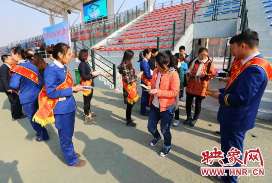 活動現(xiàn)場工作人員給同學們發(fā)放宣傳冊、環(huán)保袋。