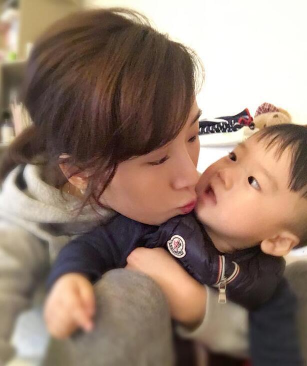 照片中李念狂吻兒子，小寶貝自顧自地玩著。