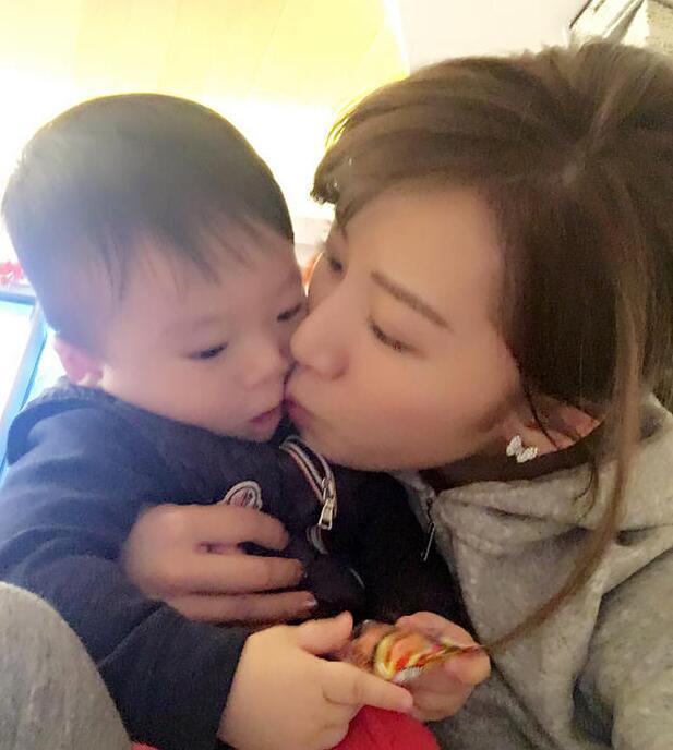 照片中李念狂吻兒子，小寶貝自顧自地玩著。