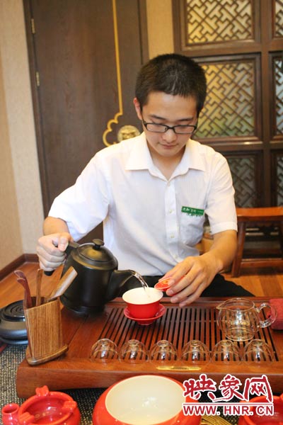 1、水壺里的水煮沸，李克勤把茶葉放進茶荷里，準備溫杯沖茶