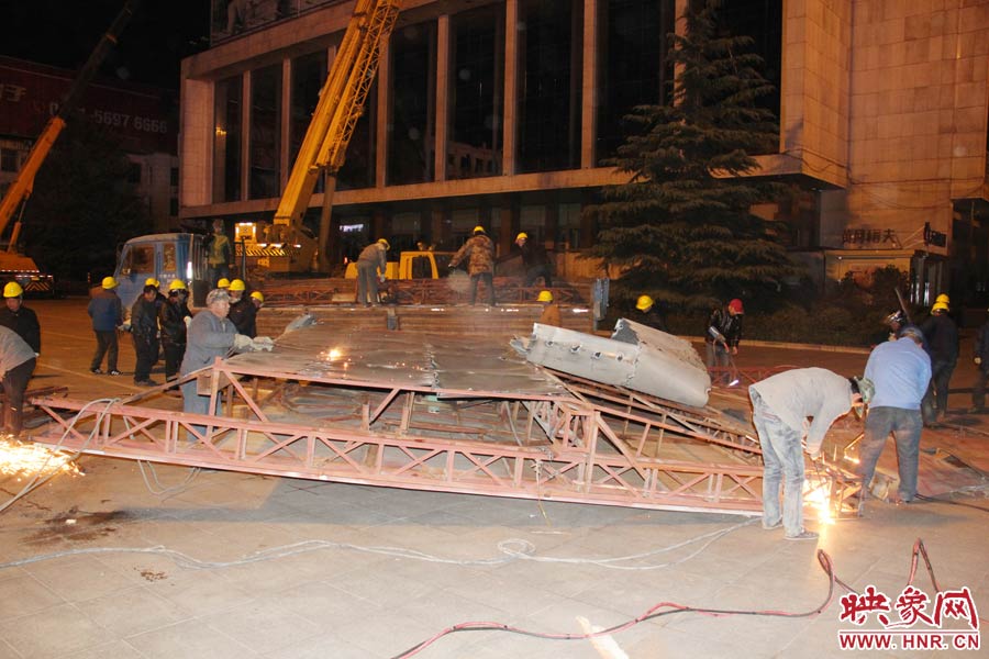 地面上的20多名工人對吊裝下的廣告牌進行分割。