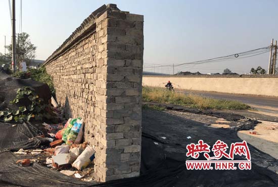 一墻之隔，一邊是道路，一邊是垃圾和荒草，市民質(zhì)疑其為遮羞墻。