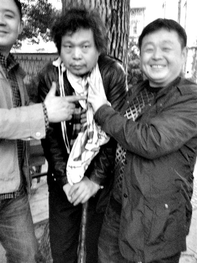 兩名接訪人員與患有癌癥的訪民段新德合影時，面帶笑容擺出勝利的手勢。