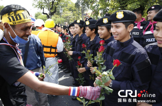2013年12月03日,曼谷總理府與曼谷警署允許反政府示威民眾進(jìn)入,雙方進(jìn)入暫時(shí)“停戰(zhàn)”狀態(tài)迎接泰王生日。曼谷警察總署,女警們手持鮮花送給反政府示威民眾。圖片來源:Manish Swarup/東方IC
