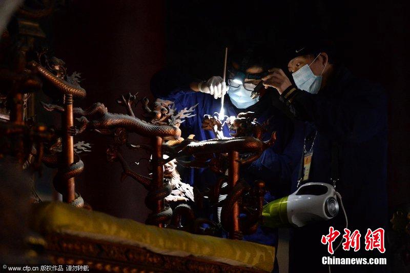 圖為工作人員使用軟毛刷和吸塵器對太和殿的金漆雕龍寶座除塵。