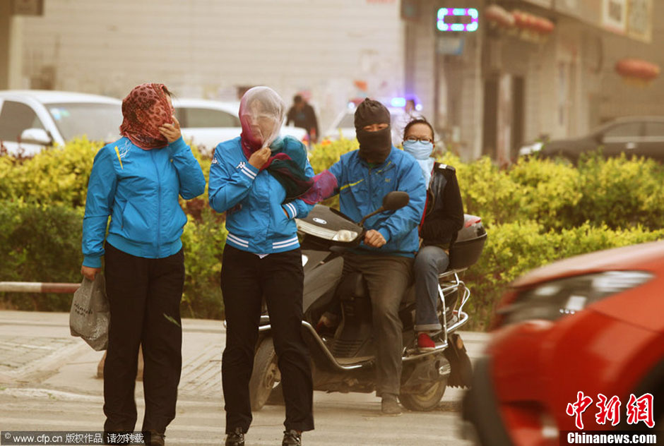 2014年04月23日，新疆維吾爾自治區(qū)吐魯番地區(qū)，市民戴著口罩行走在大風沙塵中的吐魯番市街頭。