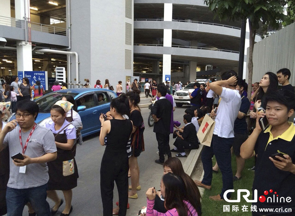 當?shù)貢r間2014年5月5日，泰國清萊，工人們站在一棟大樓外避難。