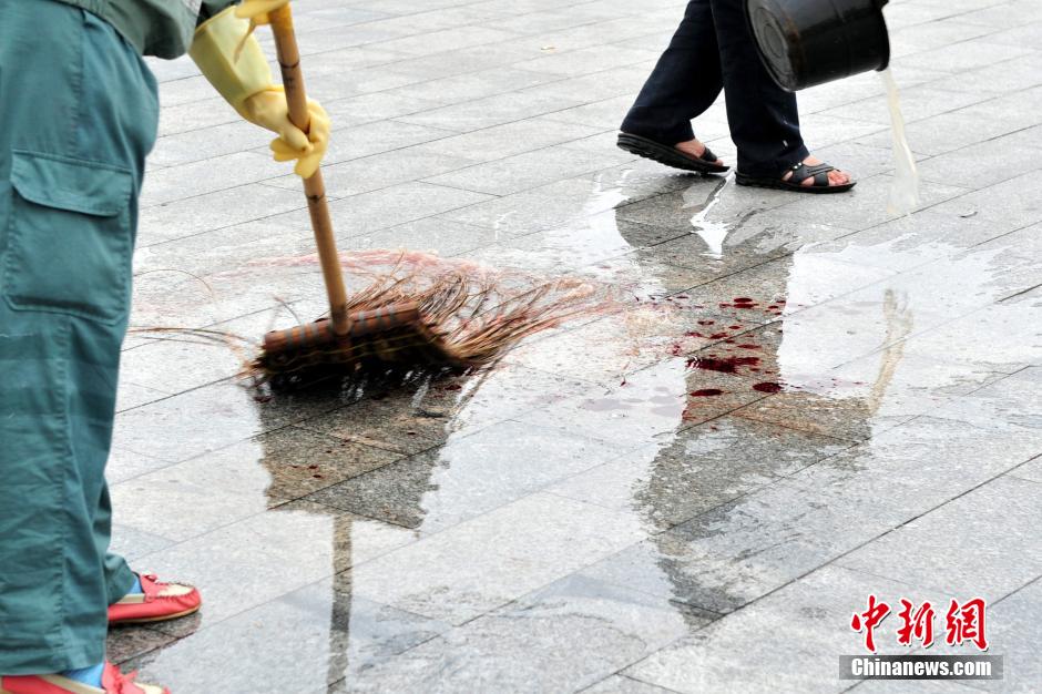 圖為環(huán)衛(wèi)工人在清理案發(fā)地點的血跡。