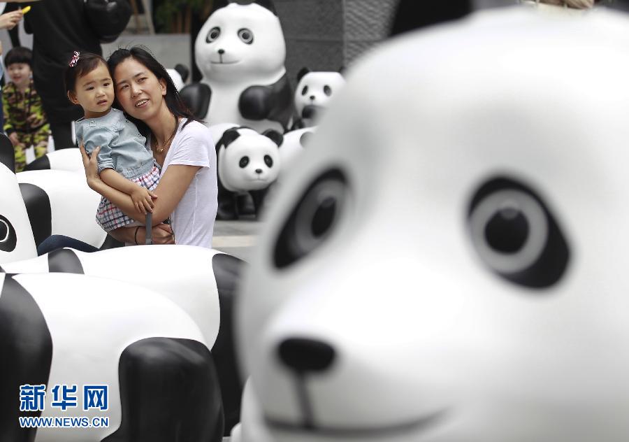 6月2日，一位家長帶著孩子在上海街頭和大熊貓模型合影。