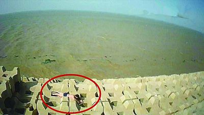 孫正龍游上岸，趴在海邊精疲力盡。