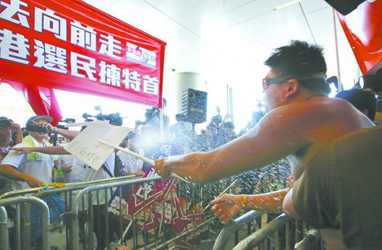 17日，在香港立法會外，一名反對政改的男子向支持派人群投擲標(biāo)牌。