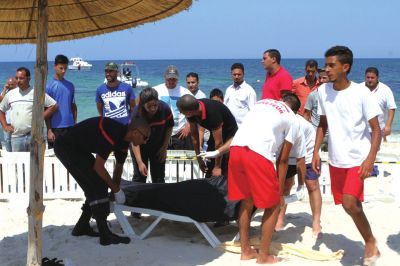 6月26日，在突尼斯蘇塞，救生員和醫(yī)務(wù)人員在發(fā)生襲擊事件的海灘運(yùn)送一名死者的遺體。新華社發(fā)