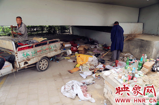 負(fù)責(zé)高架橋下綠化的人員在清理流浪漢留下的垃圾和雜物。