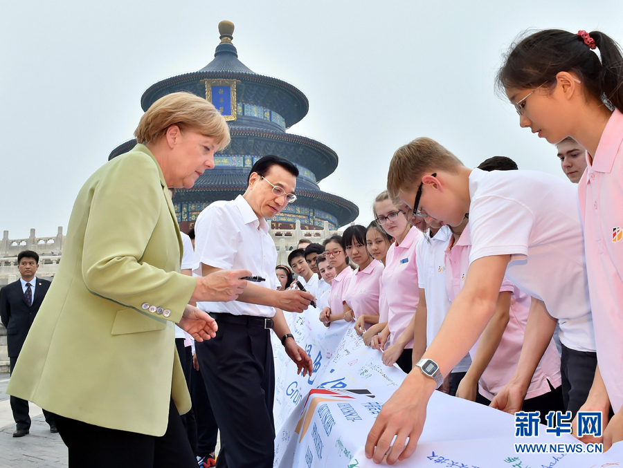 李克強(qiáng)同默克爾在紀(jì)念橫幅上簽名。