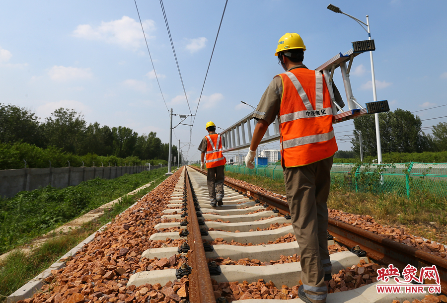 滾燙的鐵軌上，兩個扛著梯子的檢修員走向第四個檢修點
