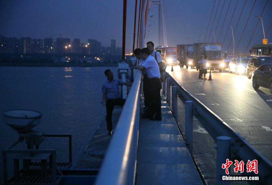 圖為武漢警方談判專家正在與翻爬至大橋外側(cè)護(hù)欄的劫持者談判。