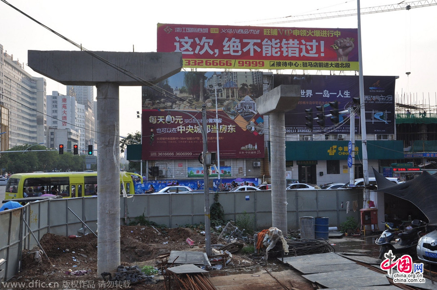 過街天橋一側(cè)的橋樁早已打好,可是對面的郵政銀行網(wǎng)點(diǎn)依舊在照常營業(yè)。