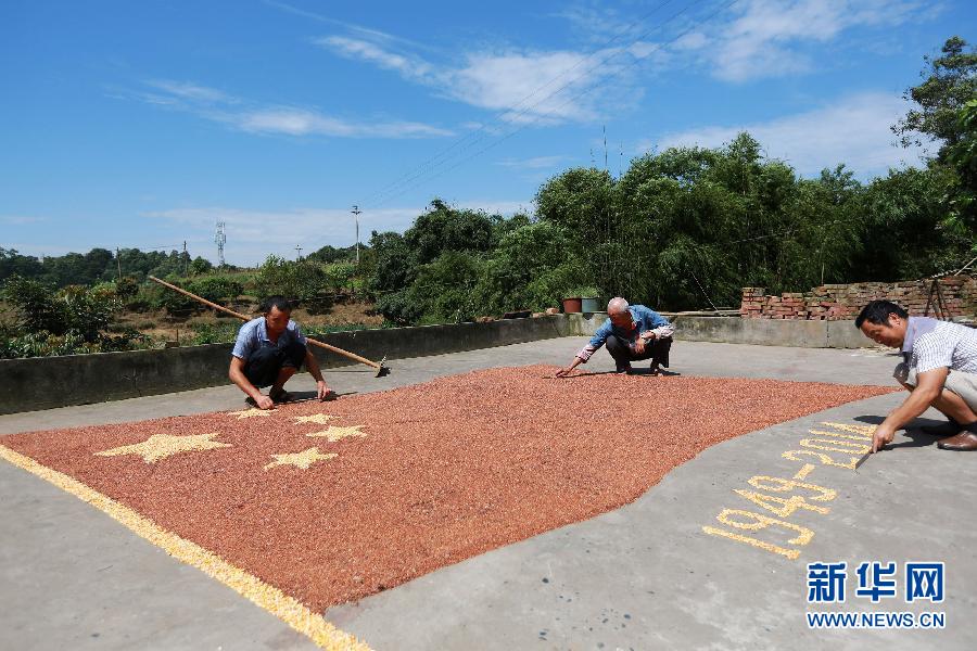 村民馬玉明（左一）用豐收的高粱和玉米在院壩里擺國旗為祖國慶生。