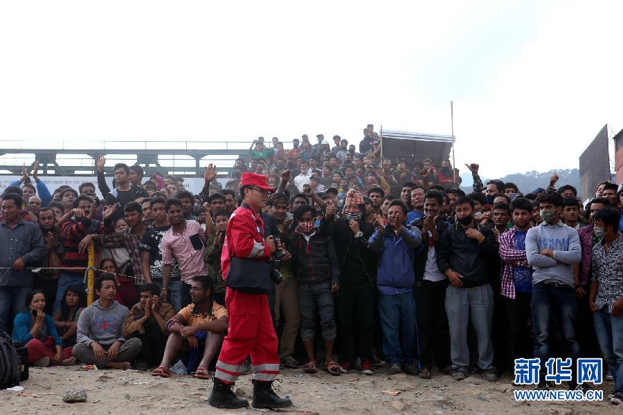 圍觀的尼泊爾民眾在中國國際救援隊(duì)成功搜救出幸存者后向搜救隊(duì)員歡呼致意。